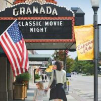 family walking past historic Granda Theatre marquee on Commercial Street in emporia