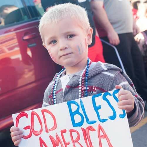 child holding a patriotic sign at Emporia's Veterans Day parade