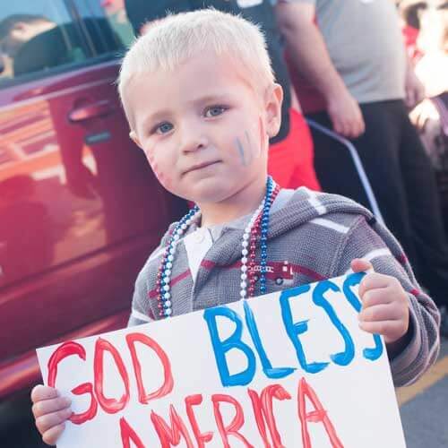 child holding a patriotic sign at Emporia's Veterans Day parade